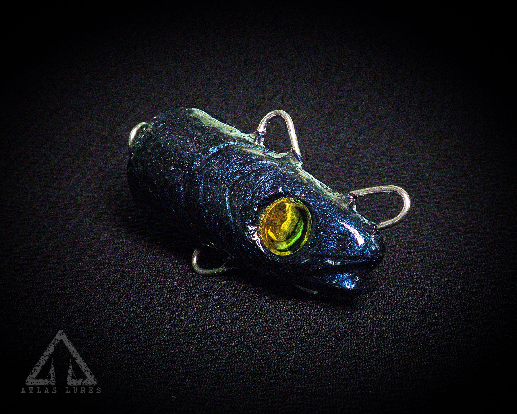 Blue fishing lure with a yellow eye on a black background, branded 'Atlas Lures'.