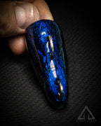 Blue and black textured object held in a hand against a dark background