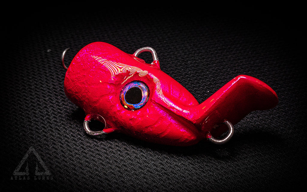 Red fishing lure with a shiny surface on a dark textured background