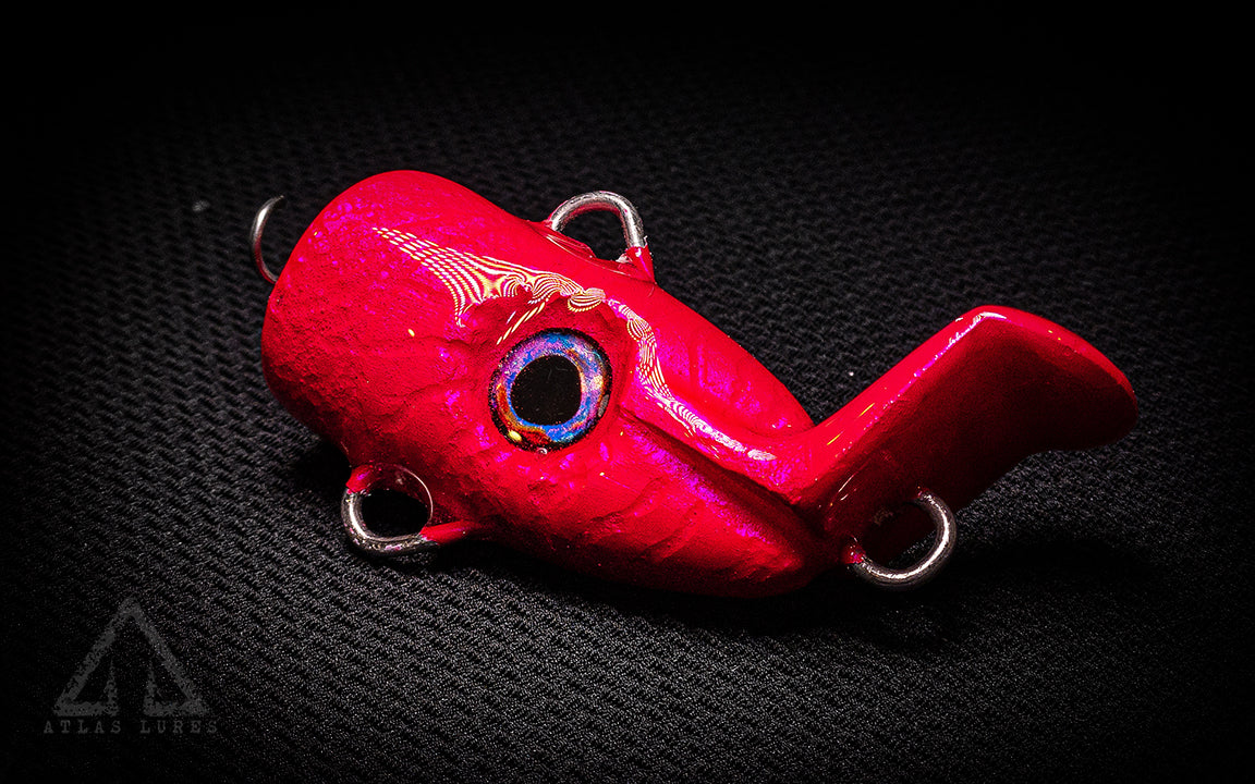Red fishing lure with a shiny surface on a dark textured background