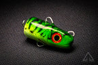 Green fishing lure with red eye on a black textured background