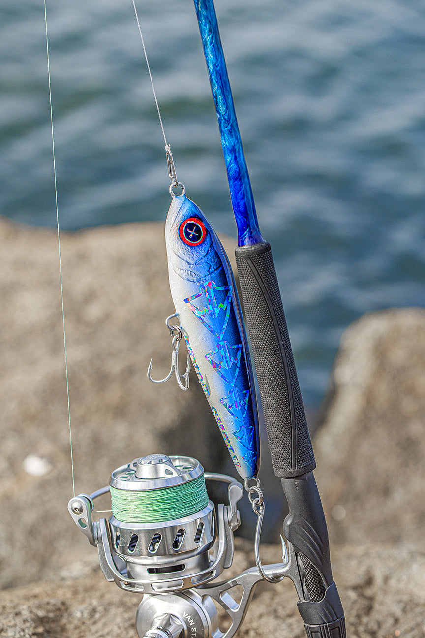 Fishing rod with blue and silver lure against a water background