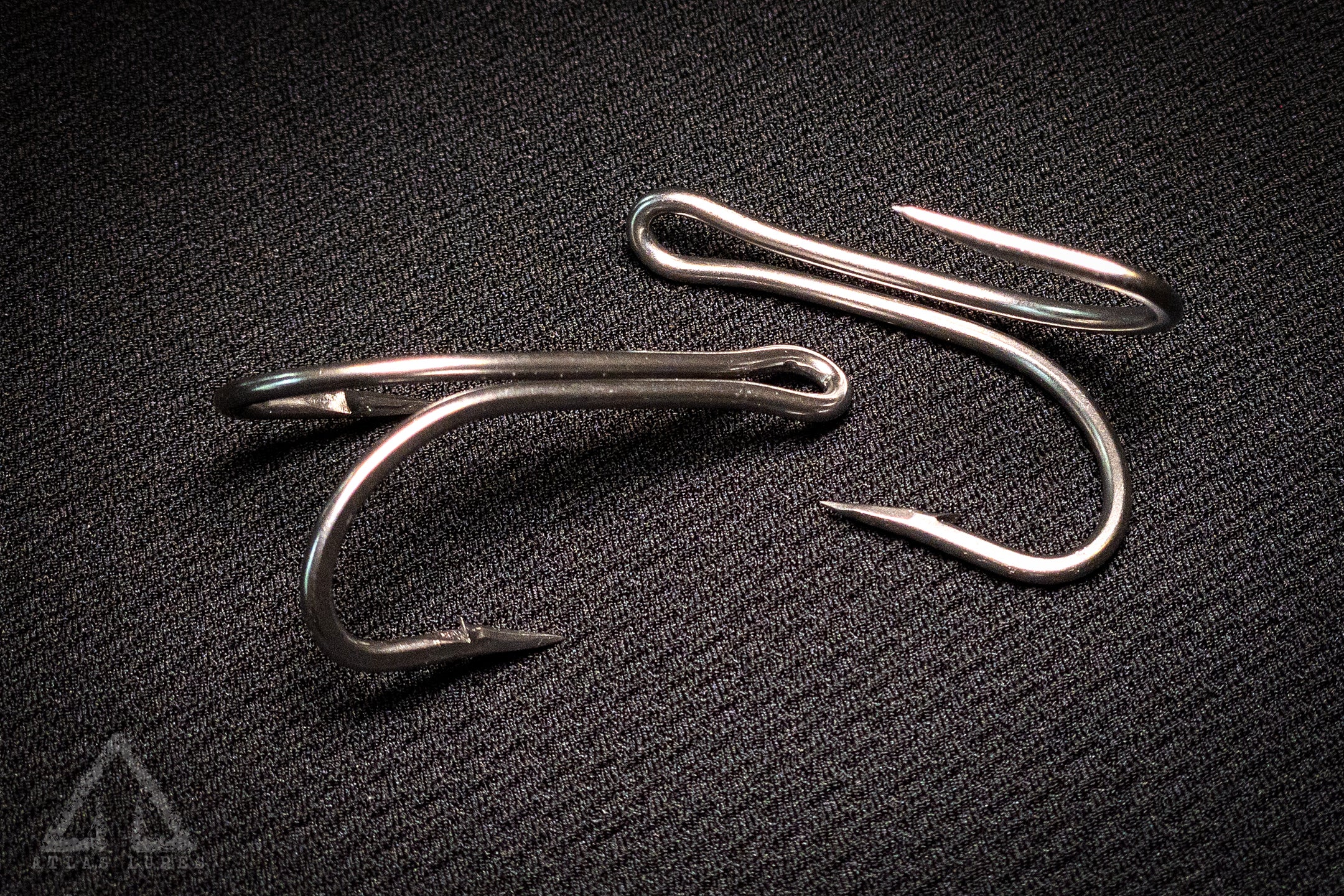 Three fishing hooks on a textured black surface