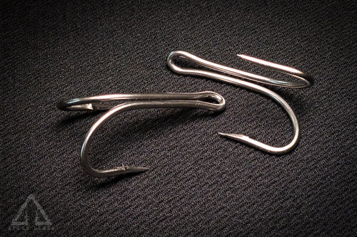 Three fishing hooks on a textured black surface