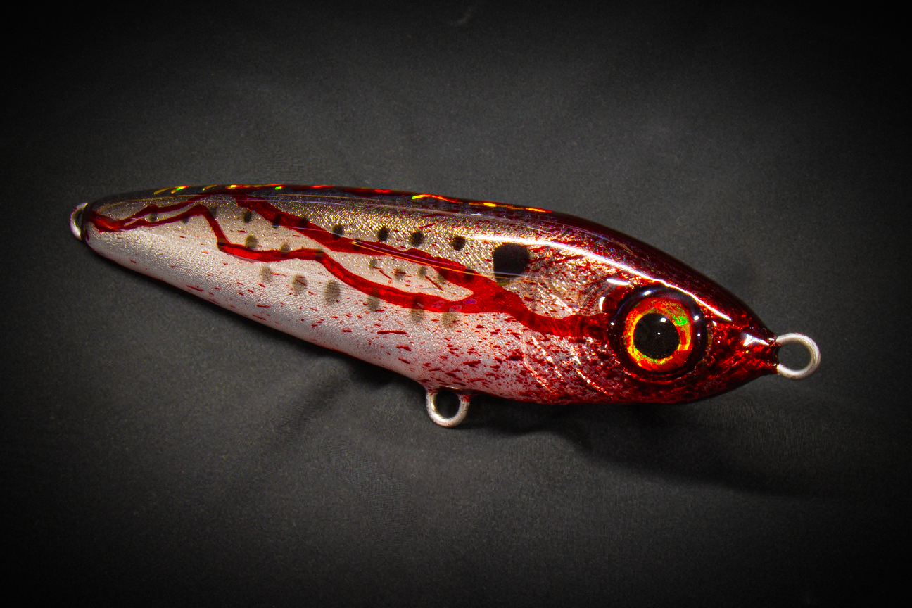 Fishing lure with red and silver pattern on a dark background