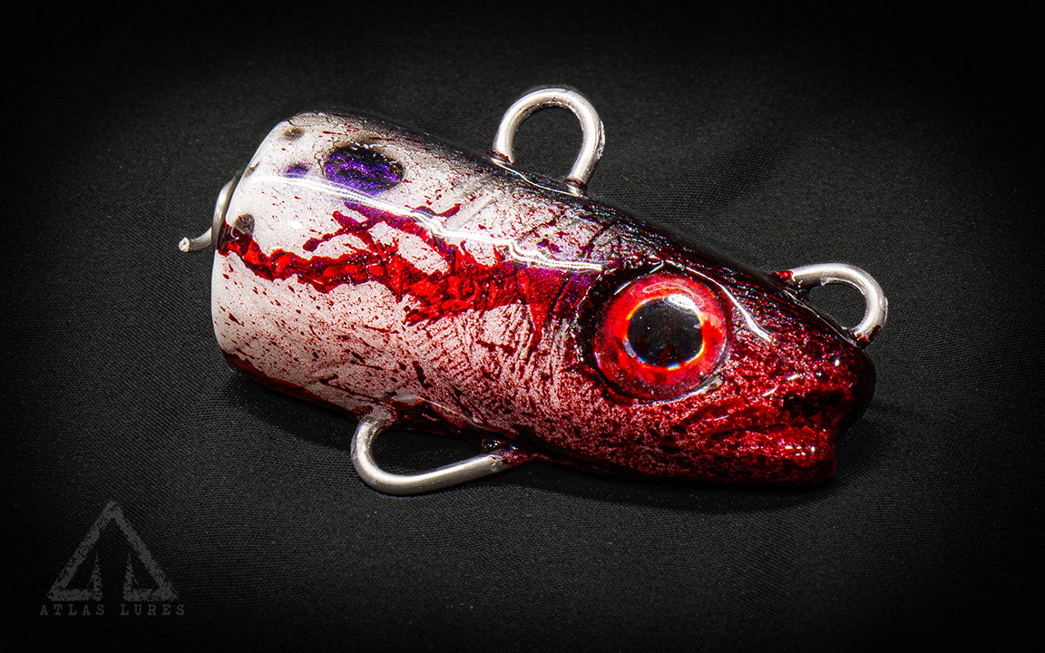 Red and white fishing lure with a dark background