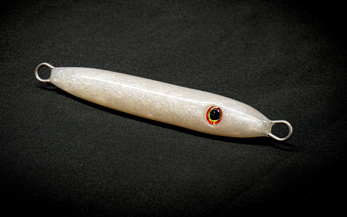 White fishing lure with a red eye on a black background