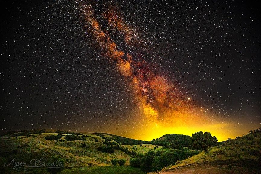 Milky Way galaxy over a landscape with green fields and trees