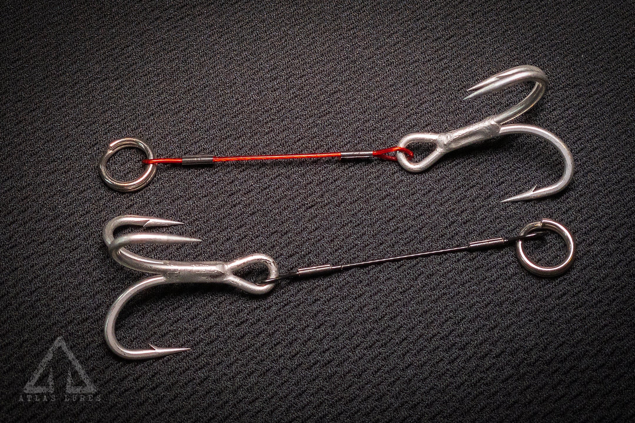 Two fishing hooks on a textured black surface