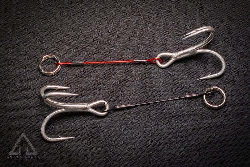 Two fishing hooks on a textured black surface