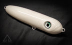 White fishing lure with a green eye on a black background