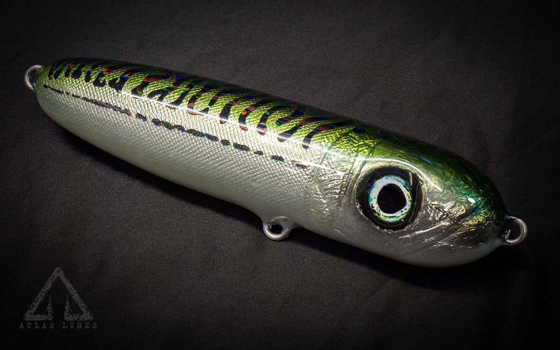 Fishing lure with metallic finish and green stripes on a dark background