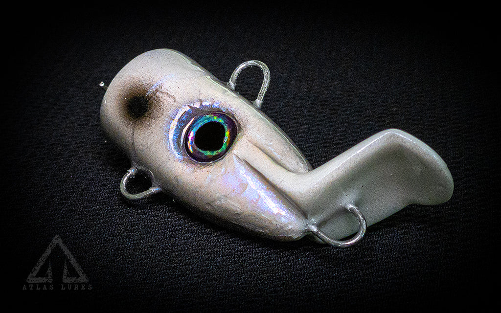 White fishing lure with a dark eye on a black background