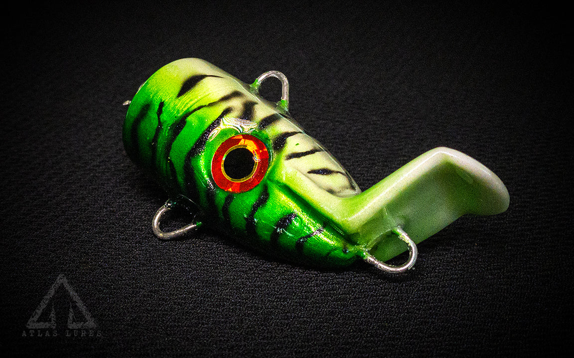Green and white fishing lure with red eye on a black background