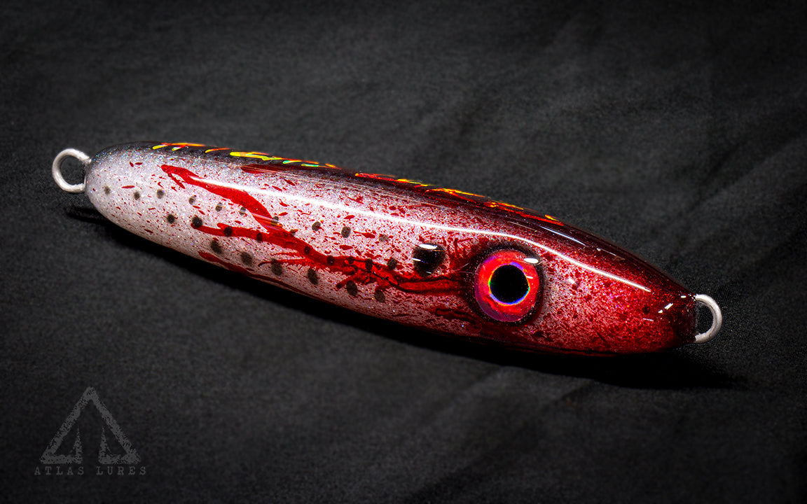 Red blood and silver fishing lure on a dark background. 