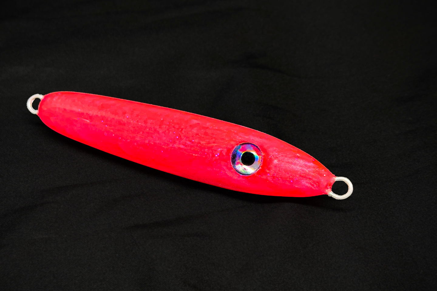 Red fishing lure with a shiny eye on a black background